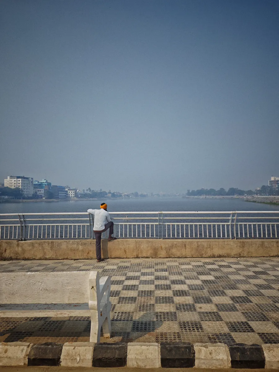 A person stands beside a railing overlooking water.