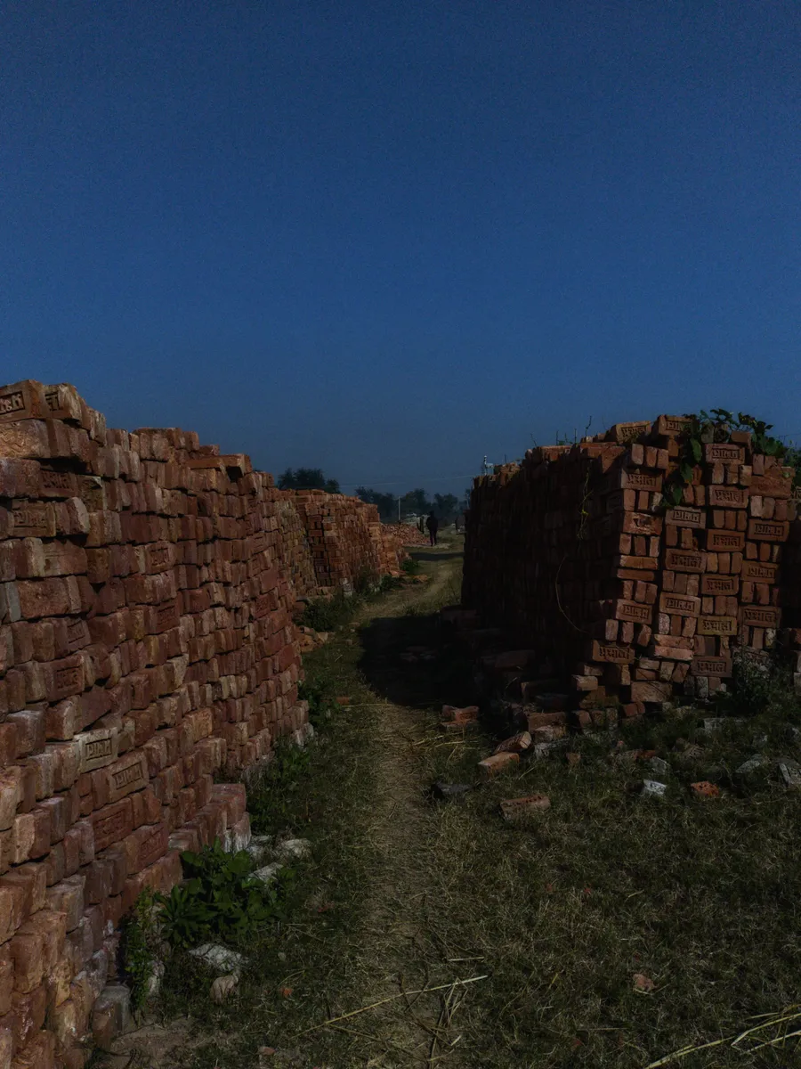 A narrow passage between stacks of red bricks.